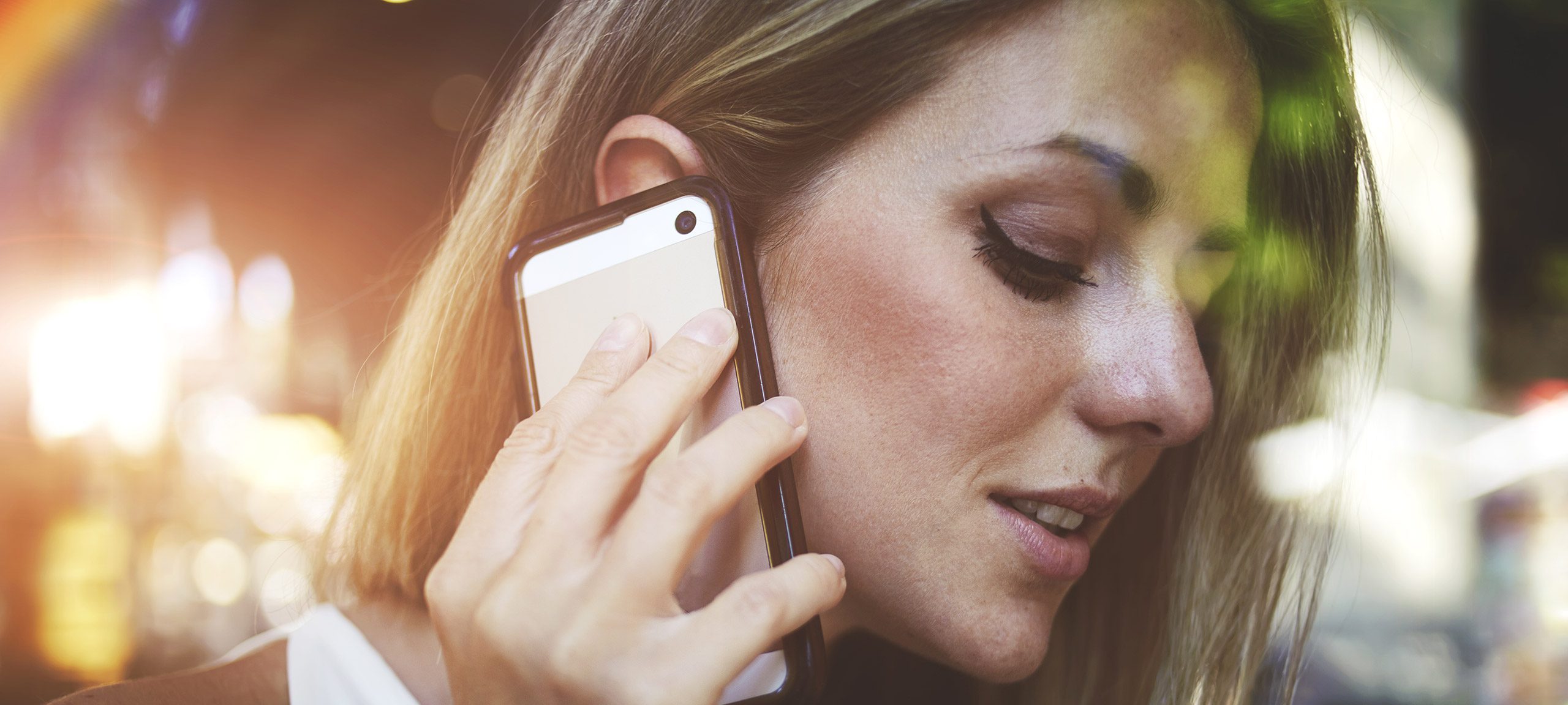 En kvinna håller sin mobiltelefon mot örat.